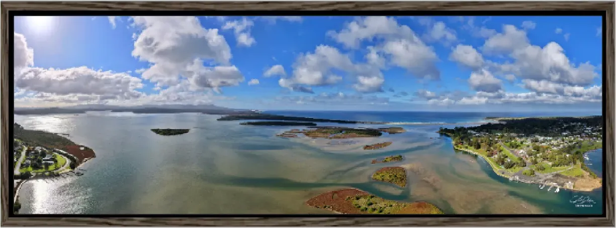 A panoramic coastal photograph presented in a walnut frame